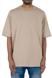 Man wearing a beige t-shirt and blue jeans on a white background
